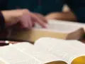 Hände studieren die Bibel, ein Symbol für tiefen Glauben und spirituelle Suche.