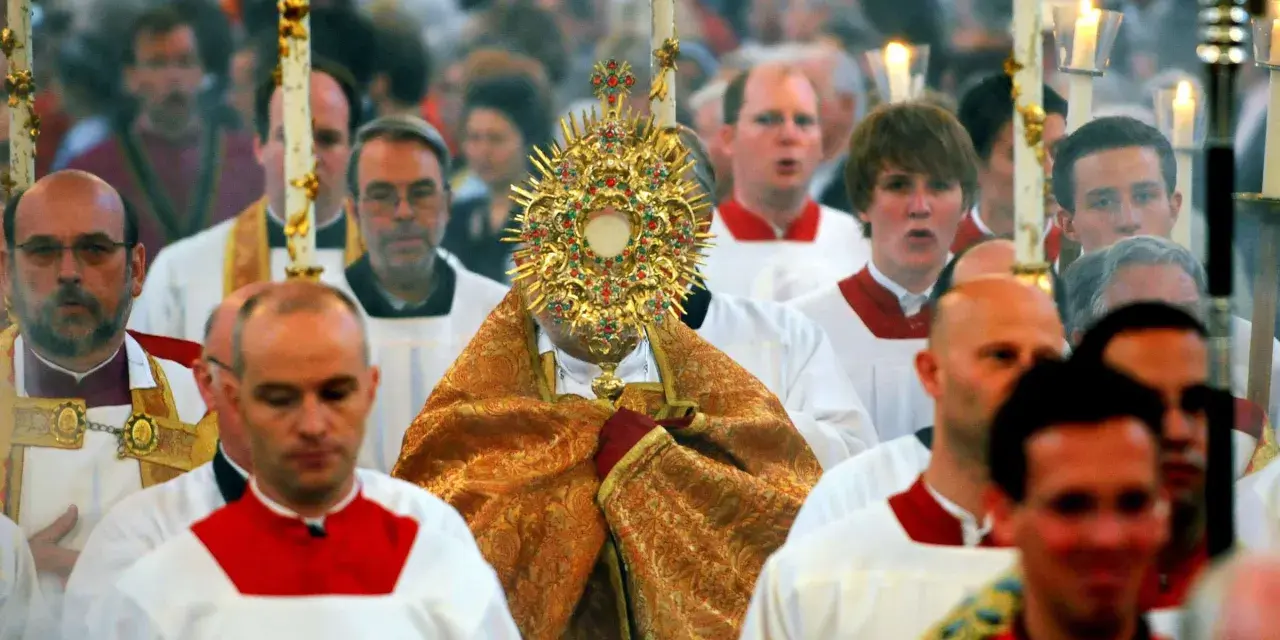 Bei Fronleichnam feiert eine Prozession mit einem goldenen Monstranz. Männer in weißen Gewändern mit roten Kragen gehen mit.