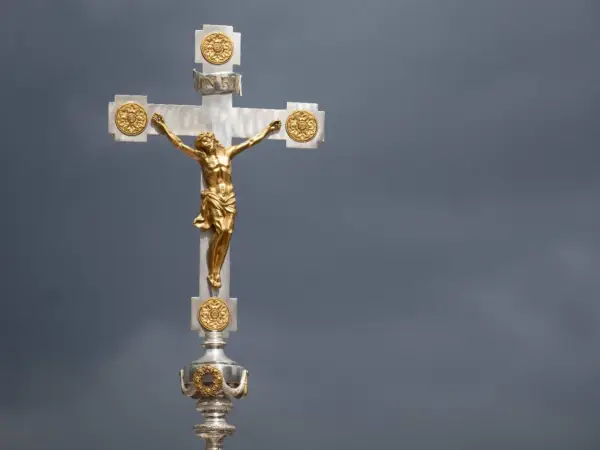 Ein goldenes Kruzifix mit Jesus vor dramatischem Himmel. Die Frage, wie lange dauert die Osterzeit, hallt nach.